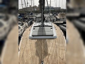 A stunning view of a yacht's deck, showcasing its sleek design and polished wood finish, docked among other vessels in a marina.