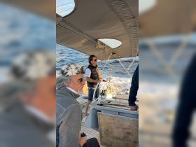Two men navigate a sailboat, enjoying the experience of sailing on open waters — a perfect moment for adventure lovers.