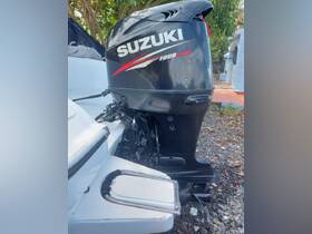 Close-up of a Suzuki four-stroke outboard motor mounted on a boat, showcasing the engine's design and features.