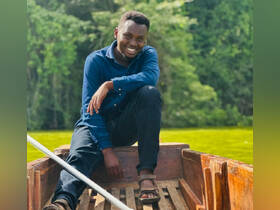 A smiling individual enjoys a moment on a boat, surrounded by lush greenery — perfect for showcasing the beauty of nature and boating experiences.