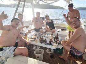 A lively group enjoys a festive gathering on a boat, sharing food and drinks while soaking up the sun — perfect for memorable celebrations on the water.