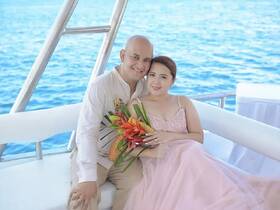 A couple poses together on a boat, surrounded by the beautiful ocean, making for a perfect romantic getaway or celebration.