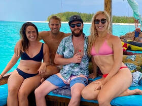 A cheerful group of friends enjoys a sunny day on a boat, showcasing the perfect beach vibe and fun in the water.