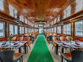 Interior view of a beautifully designed dining area on a boat, featuring elegant seating and large windows offering scenic views — perfect for onboard dining experiences.