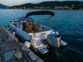 A sleek speedboat named 'Antonija' docked at a stone pier, surrounded by tranquil waters and scenic hills — perfect for a day of adventure on the water.