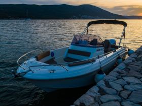 A sleek speedboat docked at sunset, showcasing its elegant design against a serene water backdrop — perfect for leisurely outings or water adventures.