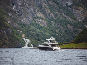 A luxurious yacht navigates through serene waters, surrounded by stunning mountainous landscapes — perfect for exploring nature's beauty.
