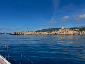 A stunning view of a rocky coastline and distant hills, captured from a boat, showcasing the serene beauty of the water and landscape.