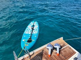 A vibrant paddleboard is secured alongside a boat, showcasing the perfect water toy for fun and relaxation on the water.