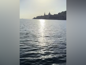 A serene view of the coastline reflecting in the water at sunset, capturing the beauty of a tranquil boating experience.
