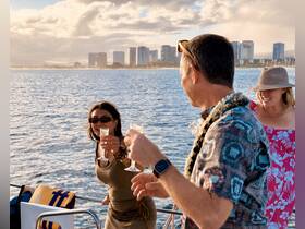 A joyful group toasts with cocktails aboard a boat, enjoying a beautiful sunset view of the city skyline — perfect for memorable celebrations on the water.