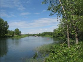 A picturesque view of a serene river with kayakers enjoying the water, surrounded by lush greenery — perfect for outdoor adventures and nature exploration.