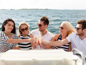 A group of friends toasts with cocktails while enjoying a sunny day on the water — perfect for celebrations and memorable outings.