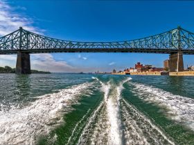 A stunning view of a bridge spanning over the water, showcasing the vibrant cityscape in the background — perfect for capturing the essence of urban boating adventures.