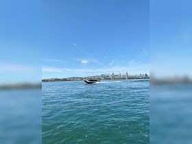 A sleek speedboat glides through the water with a vibrant city skyline in the background, perfect for thrilling water adventures.