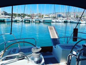 A view from the helm of a boat, showcasing the interior design and layout, with a glimpse of the marina in the background.