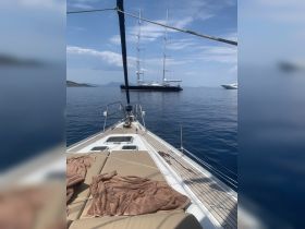A serene view from the bow of a yacht, showcasing another majestic vessel in the distance, perfect for luxury sailing experiences in calm waters.
