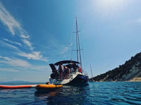 A lively scene of friends enjoying paddleboarding and sailing on a sunny day, showcasing the perfect blend of adventure and relaxation on the water.