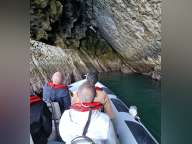 A group of adventurers explores a stunning cave by boat, showcasing the beauty of nature and the thrill of discovery.