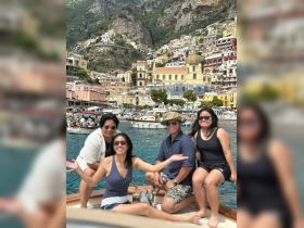 A joyful group poses on a boat with the stunning Amalfi Coast in the background, capturing the essence of a perfect day on the water.