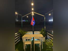 A cozy dining area on a boat, featuring a table and chairs illuminated by string lights, perfect for evening gatherings.