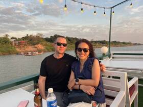A couple enjoys a scenic sunset on a boat, sharing drinks and smiles — perfect for romantic getaways or special celebrations.