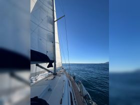 A stunning view of a sailboat underway, showcasing its sleek design against a clear blue sky and shimmering waters — perfect for sailing enthusiasts.