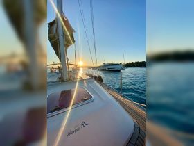 A stunning sunset view from the deck of a Hanse sailboat, showcasing the tranquil waters and nearby yachts — perfect for evening cruises.