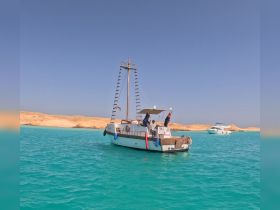 A lively group enjoys a day on a boat in stunning turquoise waters, with a picturesque beach backdrop — perfect for memorable outings and adventures.