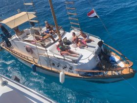 A lively group enjoys sunbathing on a boat in crystal-clear waters, perfect for a tropical getaway or a fun day at sea.