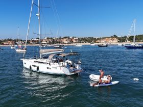 A group enjoys a sunny day paddleboarding near a yacht, capturing the essence of summer fun on the water.