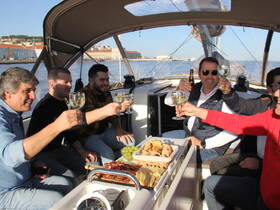 A group of friends raises their glasses in a toast aboard a yacht, enjoying a delightful spread of food and drinks — perfect for celebrations on the water.