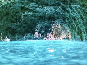 A group of kayakers explores a stunning cave with vibrant blue waters, showcasing the beauty of nature and adventure on the water.