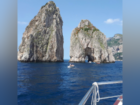 A stunning view of the iconic Faraglioni rock formations in Capri, with boats navigating the crystal-clear waters — a perfect destination for sightseeing and exploration.