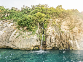 A stunning view of a rocky coastline featuring a cascading waterfall, perfect for showcasing the natural beauty of coastal adventures.