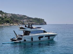 A stylish yacht anchored in serene waters with guests enjoying the sun and beautiful coastal scenery — perfect for a relaxing day on the water.