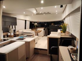 A modern and spacious interior of a yacht featuring a well-equipped kitchen and comfortable seating areas, perfect for relaxing and entertaining while on the water.