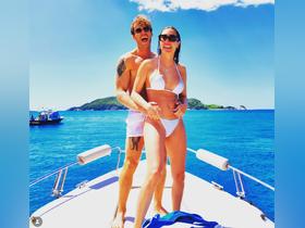 A joyful couple enjoys a sunny day on a boat, embracing each other against a stunning ocean backdrop — perfect for romantic getaways or summer adventures.