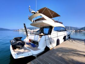 A stunning view of a Prestige 500 yacht docked at a marina, showcasing its sleek design and luxurious features against a clear blue sky.