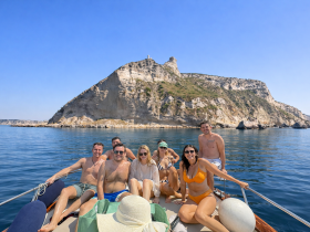 A cheerful group of friends enjoys a day on the water, posing on their boat with a stunning island backdrop — perfect for memorable adventures and celebrations.