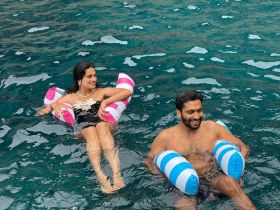 A couple enjoys a playful moment in the water, floating with colorful inflatable rings — a perfect snapshot of summer fun and relaxation.