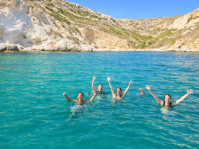 A joyful group of friends swims in crystal-clear waters, celebrating their day at the beach — a perfect snapshot of summer fun and adventure.