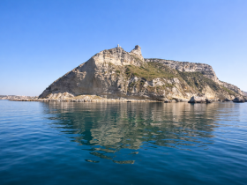 A stunning view of a rocky island coastline reflecting in calm waters, perfect for showcasing the natural beauty of the area.