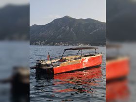 A striking red speedboat named 'Negroni' docked on calm waters, with a scenic mountain backdrop, perfect for exploring coastal destinations.
