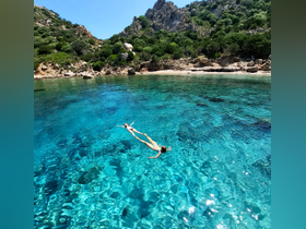 Two friends enjoy a refreshing swim in crystal-clear waters, surrounded by stunning natural scenery — a perfect moment for relaxation and fun in the sun.