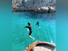 A child joyfully leaps into the crystal-clear waters while another swimmer enjoys the underwater experience, showcasing a fun day of snorkeling and adventure.