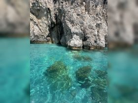 A scenic view of rocky cliffs above clear turquoise waters, showcasing the natural beauty of the coastline.
