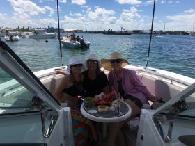A cheerful group of friends enjoys snacks and drinks aboard a boat on a sunny day, perfect for a fun day out on the water.