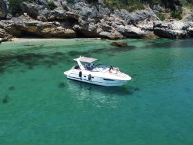 A couple enjoys a relaxing moment on a boat in crystal-clear turquoise waters, with a stunning rocky coastline in the background — perfect for romantic getaways or scenic tours.