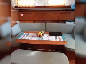 Cozy interior of a boat featuring a dining area with a fruit basket and a laptop, perfect for relaxing and enjoying meals while at sea.